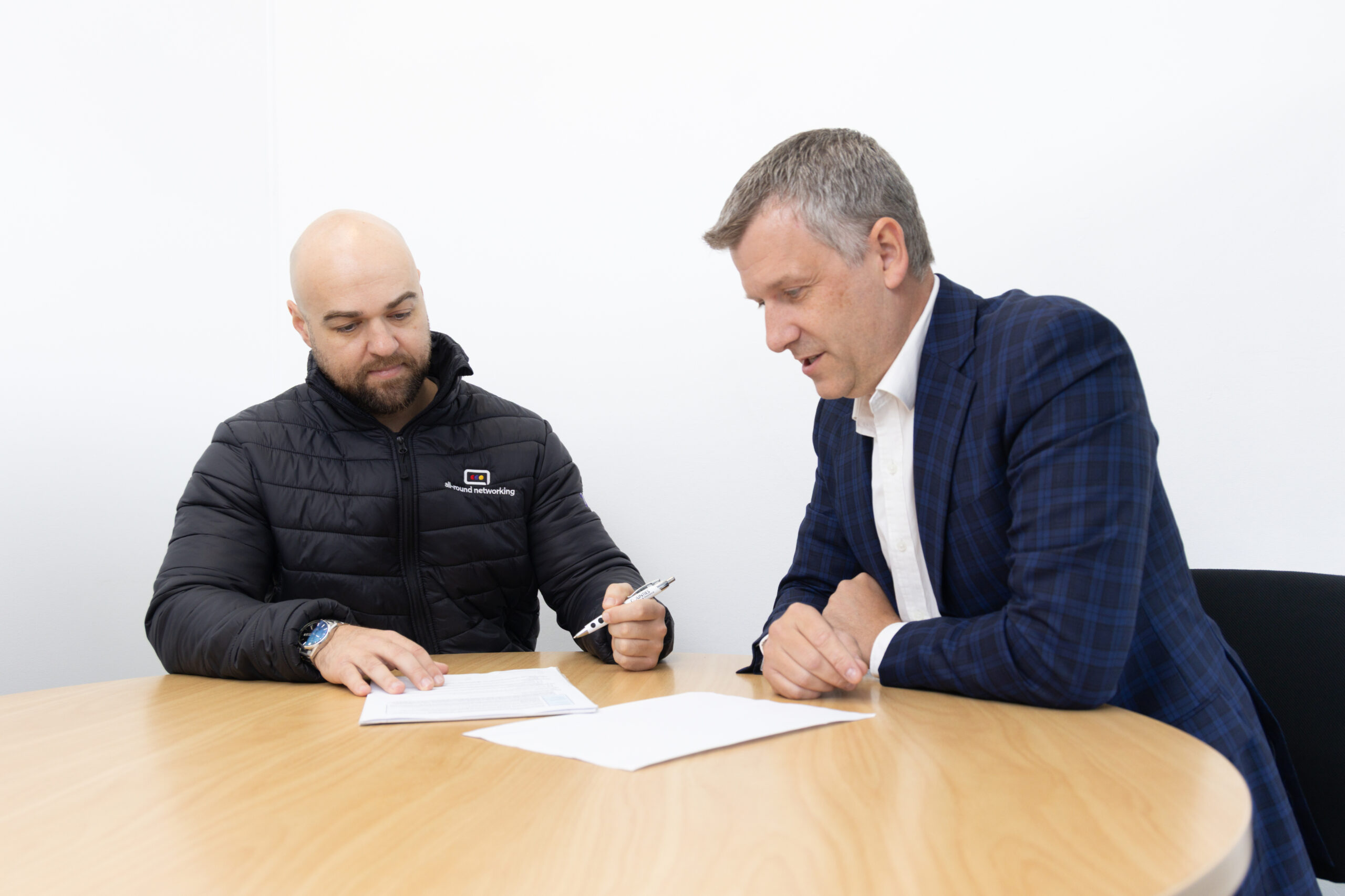 Two people signing documents at a table