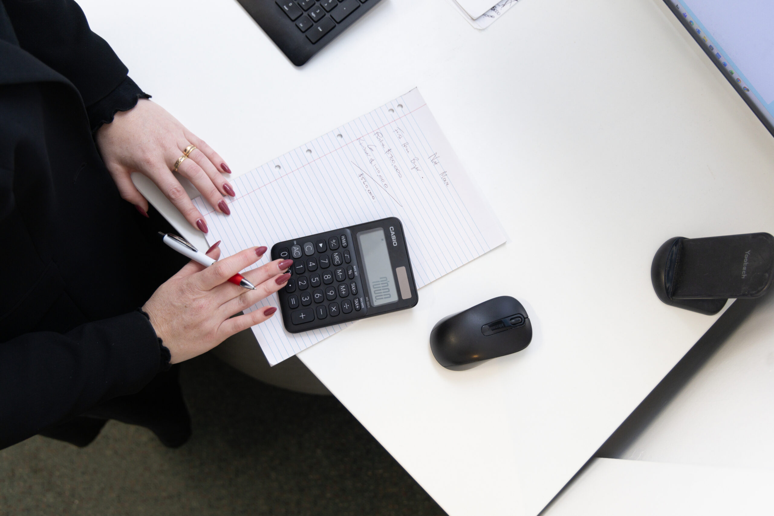 Person calculating figures with a calculator and pen